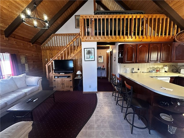 living area featuring a chandelier, beamed ceiling, wood walls, wood ceiling, and stairs