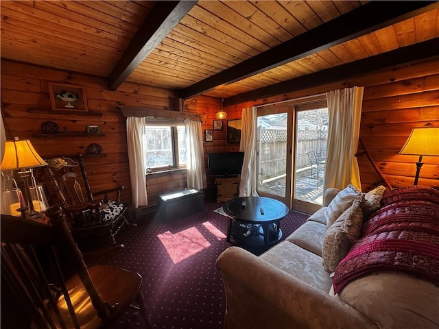 carpeted living room featuring beam ceiling, wooden walls, and wooden ceiling