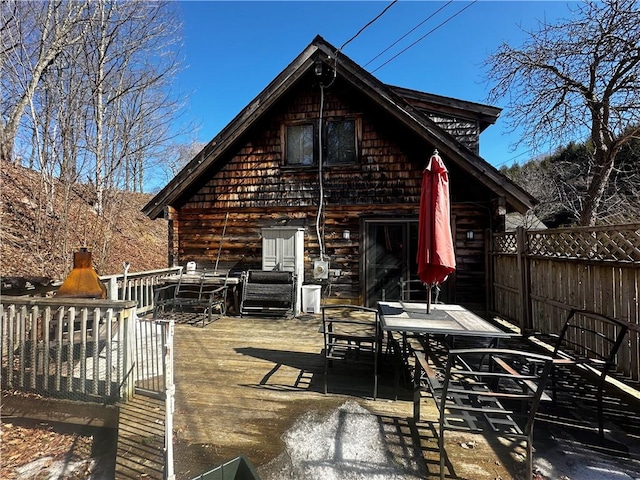 back of property with outdoor dining space, a patio area, a deck, and fence