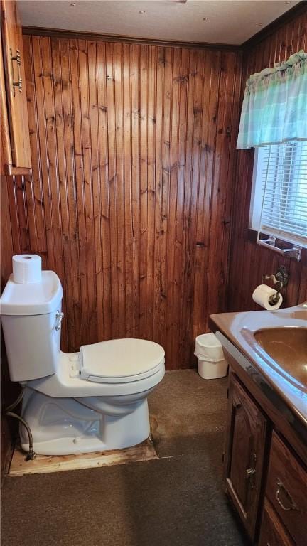 bathroom with toilet, wood walls, and vanity