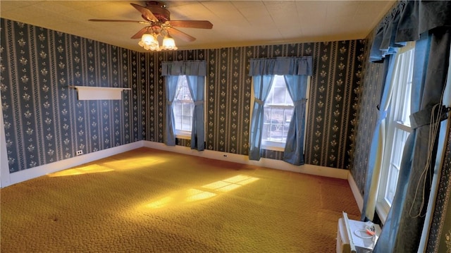 carpeted empty room with wallpapered walls, baseboards, and ceiling fan