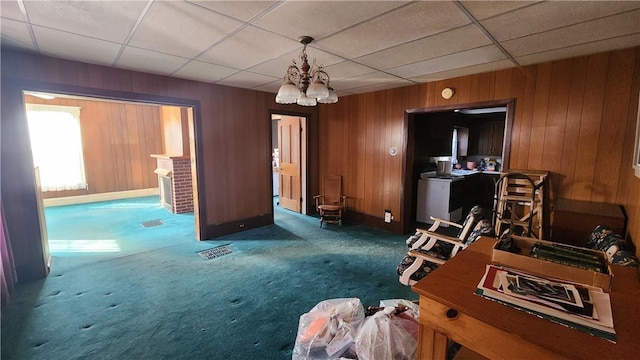 interior space featuring wooden walls, a paneled ceiling, and carpet floors