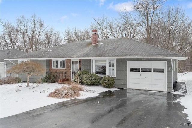 single story home with driveway, roof with shingles, a chimney, a garage, and brick siding