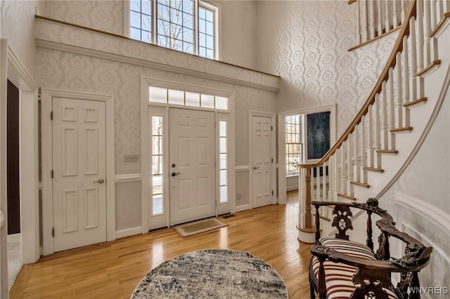 foyer featuring light wood finished floors, a healthy amount of sunlight, and wallpapered walls