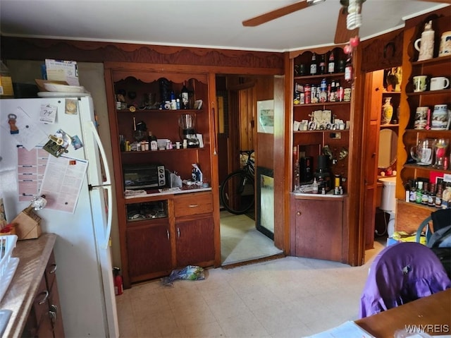 kitchen with a ceiling fan, open shelves, freestanding refrigerator, a toaster, and light countertops