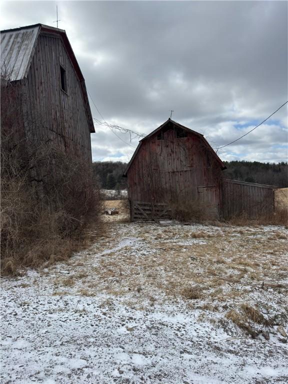 yard layered in snow featuring an outbuilding and a barn