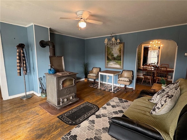 interior space featuring hardwood / wood-style floors, a wood stove, arched walkways, crown molding, and ceiling fan with notable chandelier