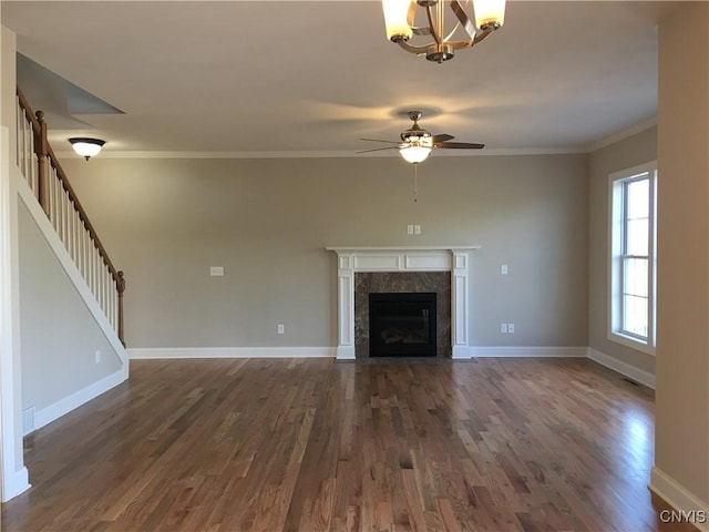 unfurnished living room with baseboards, stairway, a premium fireplace, ornamental molding, and dark wood-style floors