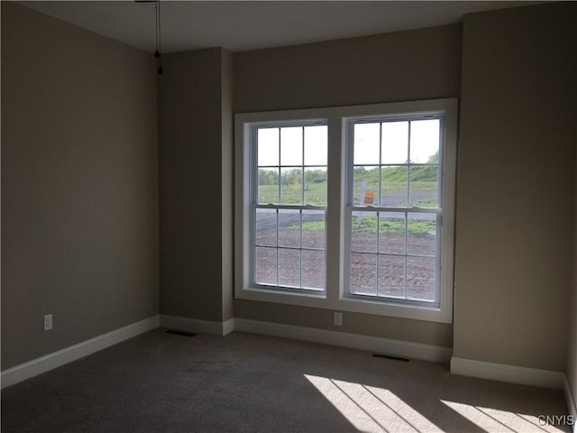 carpeted spare room featuring visible vents and baseboards