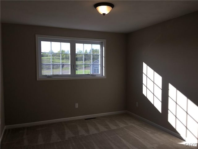 carpeted spare room with visible vents and baseboards