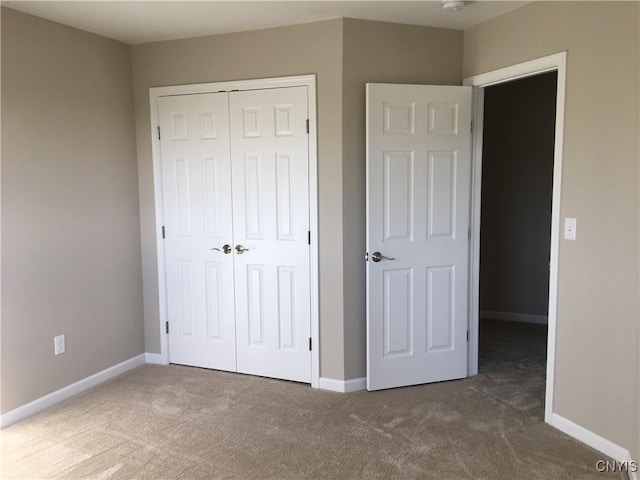 unfurnished bedroom with a closet, baseboards, and carpet floors