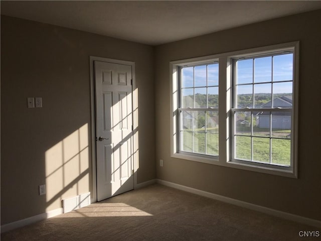 carpeted empty room featuring baseboards