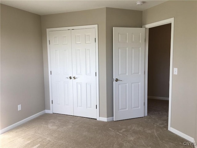 unfurnished bedroom with carpet flooring, baseboards, and a closet