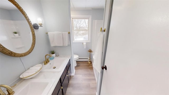 6339 County Road 32, North Norwich, NY 13815 - bathroom featuring baseboard heating, wood finished floors, double vanity, and a sink