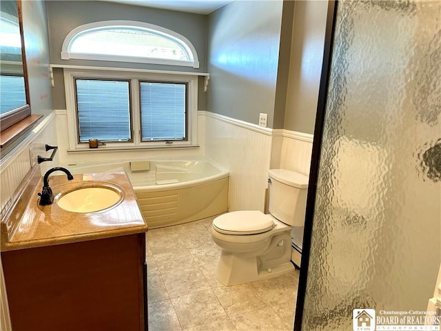 full bath with vanity, a bath, wainscoting, toilet, and baseboard heating