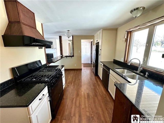 kitchen featuring black appliances, a sink, dark wood-style floors, exhaust hood, and a fireplace