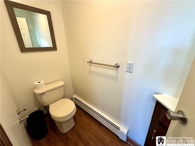 half bathroom featuring a baseboard heating unit, toilet, wood finished floors, and vanity