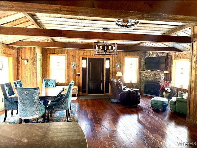 dining space featuring a stone fireplace, wood walls, and hardwood / wood-style flooring