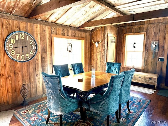 dining space with hardwood / wood-style floors, lofted ceiling with beams, and wooden walls