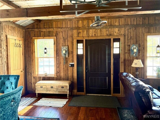 entrance foyer with wooden walls, lofted ceiling with beams, and wood-type flooring