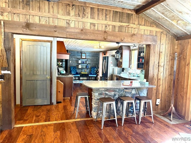 kitchen with wood finished floors, wood walls, and freestanding refrigerator