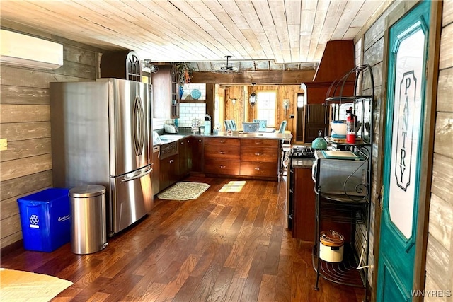 kitchen with a wall mounted AC, dark wood-style floors, freestanding refrigerator, wood walls, and wooden ceiling