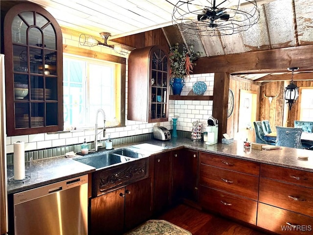 kitchen featuring a sink, backsplash, wood walls, and stainless steel dishwasher