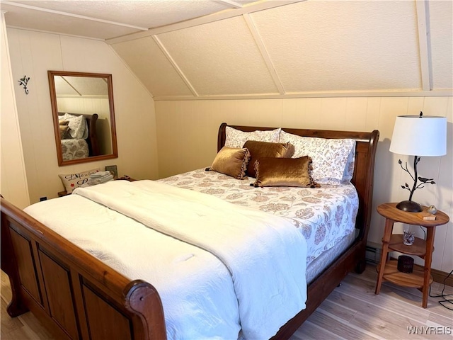 bedroom with light wood-type flooring and vaulted ceiling