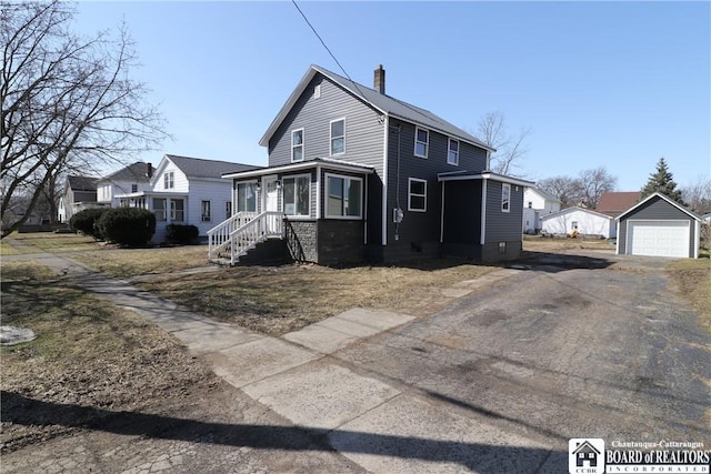 view of front facade featuring aphalt driveway, a garage, a chimney, and an outdoor structure