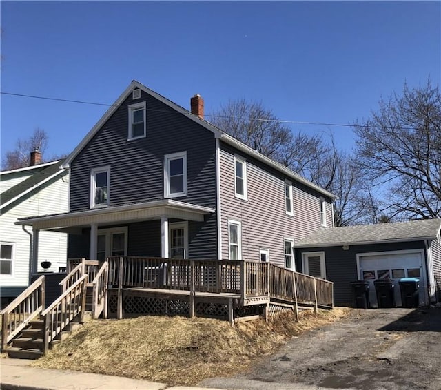 view of front of home featuring a chimney, driveway, a porch, and an attached garage