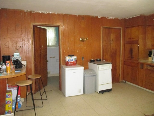 kitchen featuring brown cabinetry, wood walls, and fridge