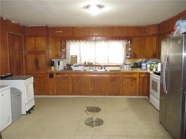 kitchen with a sink, freestanding refrigerator, white electric stove, brown cabinetry, and light floors