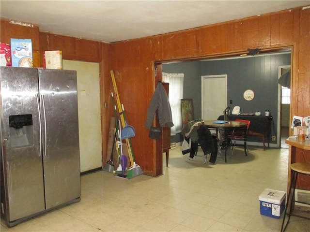 interior space with stainless steel fridge, light floors, and wood walls