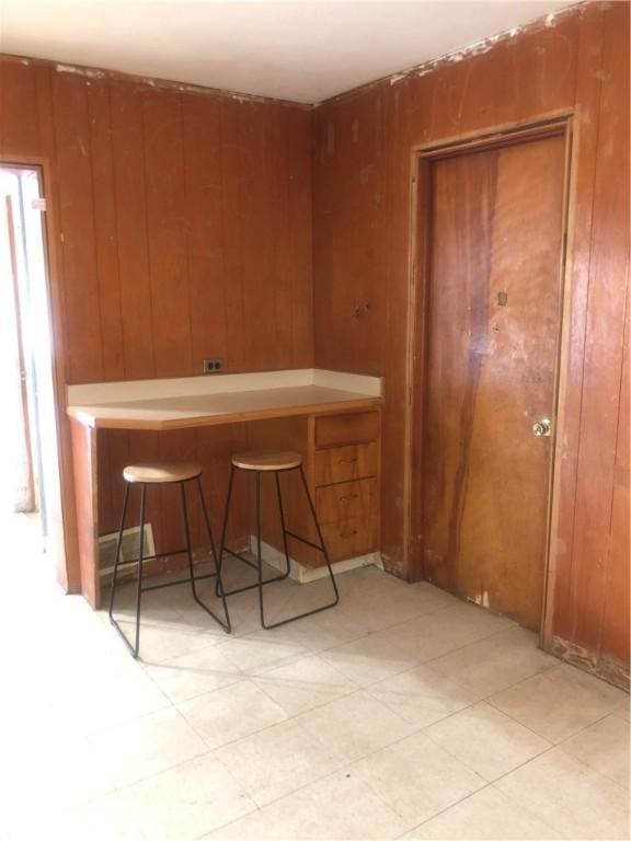 15 8th St, Oneonta-City, NY 13820 - kitchen with wooden walls, a breakfast bar area, brown cabinetry, and light floors