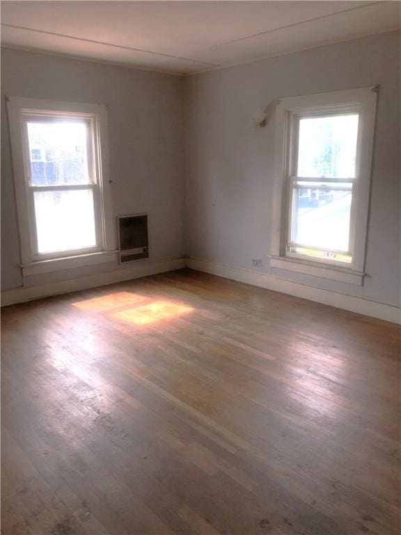 15 8th St, Oneonta-City, NY 13820 - unfurnished living room with wood finished floors, healthy amount of natural light, baseboards, and heating unit