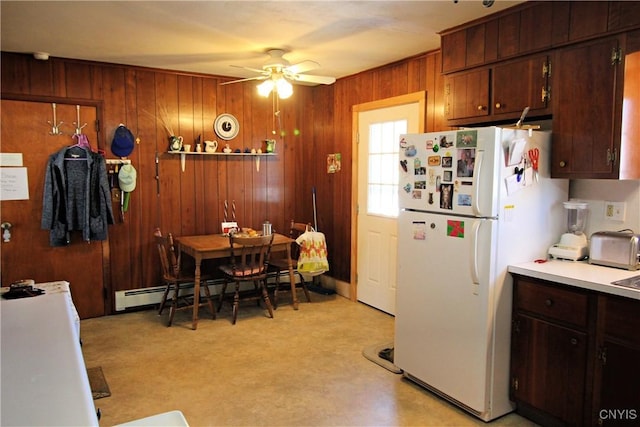 kitchen with a baseboard heating unit, freestanding refrigerator, wood walls, light countertops, and ceiling fan