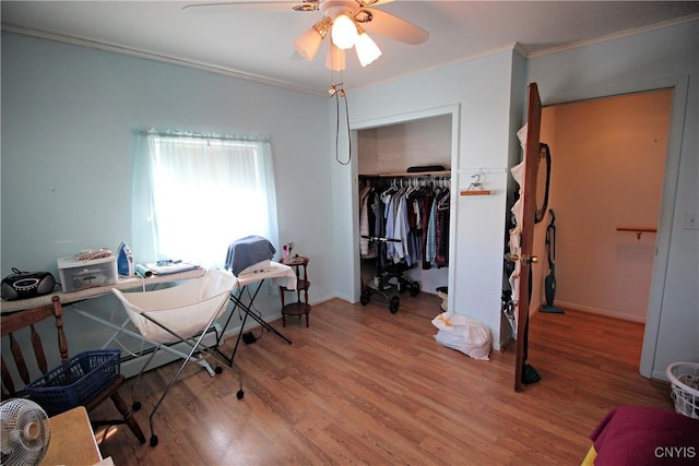 bedroom with ornamental molding, wood finished floors, a closet, baseboards, and ceiling fan