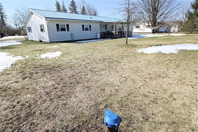 rear view of property featuring metal roof and a yard