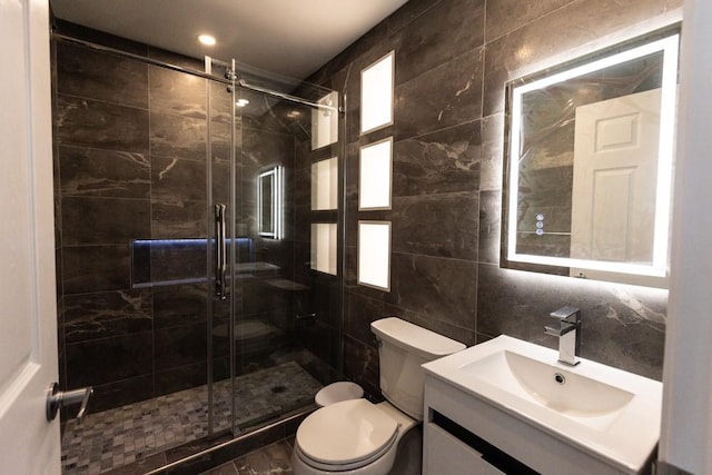 full bath featuring vanity, a shower stall, tile walls, toilet, and backsplash