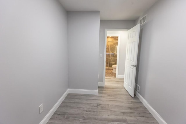 corridor with visible vents, baseboards, and light wood-style floors