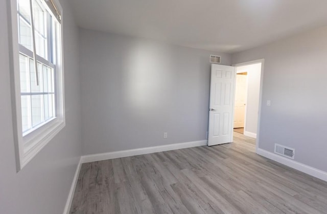 spare room featuring wood finished floors, baseboards, and visible vents