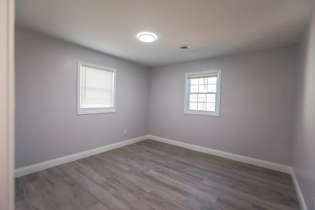 unfurnished room with visible vents, baseboards, and wood finished floors