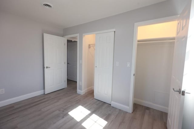 unfurnished bedroom with visible vents, baseboards, and wood finished floors