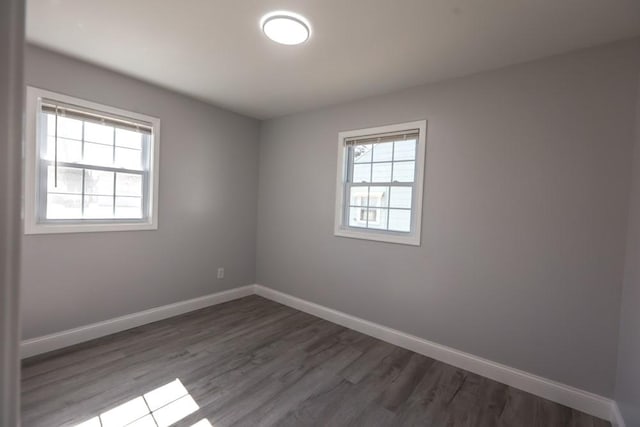 spare room featuring baseboards and wood finished floors