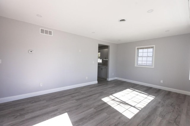 spare room featuring visible vents, baseboards, and wood finished floors