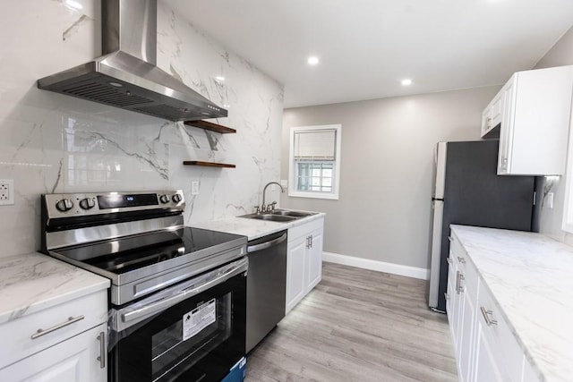 kitchen featuring a sink, backsplash, white cabinetry, appliances with stainless steel finishes, and wall chimney exhaust hood