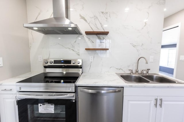 kitchen with a sink, stainless steel appliances, backsplash, and wall chimney range hood