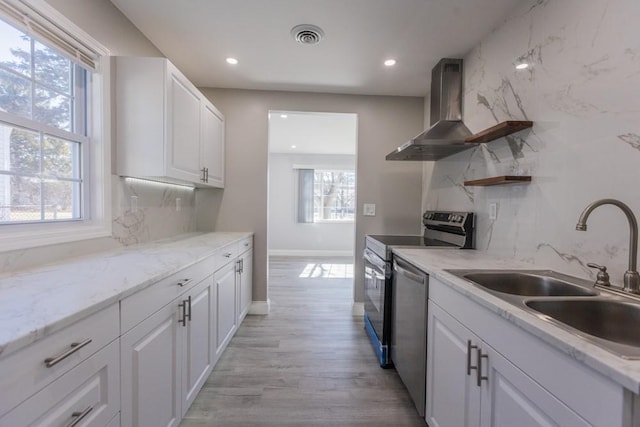 kitchen with open shelves, a sink, white cabinetry, appliances with stainless steel finishes, and wall chimney range hood