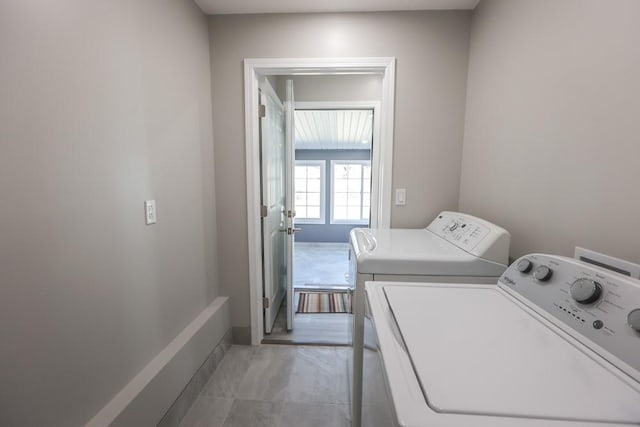 washroom featuring baseboards, washing machine and dryer, and laundry area