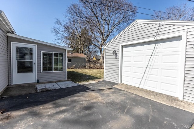 garage featuring aphalt driveway and fence